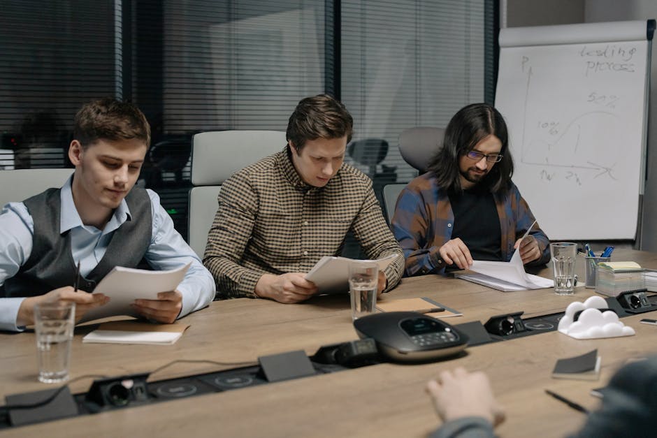 Three business colleagues reviewing documents in a modern conference room during a daytime meeting.